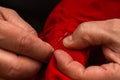 Sanior old man or woman Sews with a needle and thread at home. Fingers hands of the seamstress is using a needle and red thread to Royalty Free Stock Photo