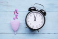 Sanitary cup with pills near an alarm clock on table Royalty Free Stock Photo