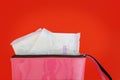 Sanitary napkin in women`s pink bag on red background