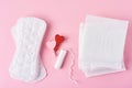 Sanitary pad, menstrual tampon and wooden red heart on a pink background,top view