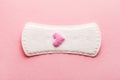 Sanitary pad with pink woolen heart as blood drop on pastel rose background, menstruation cycle, intimate hygiene Royalty Free Stock Photo
