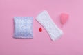 Sanitary pads and menstrual cup on pink background.