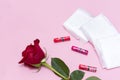 Sanitary pads in white packaging, 3 tampons, 1 red rose flower on a pink background Royalty Free Stock Photo