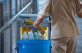 Sanitary set on tray with cleaning man, bottle of hygiene liquid with mop and bloom and bin for clean public area