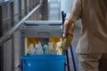 Sanitary set on tray with cleaning man, bottle of hygiene liquid with mop and bloom and bin for clean public area