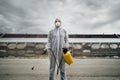 Sanitation worker in hazmat protection suit and N95 mask with chemical decontamination sprayer tank.Disinfecting streets and