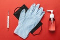 Sanitizer bottle, Medical surgical mask, lab gloves and thermometer - Virus protection equipment on red background Royalty Free Stock Photo