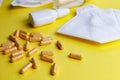 Sanitizer, protective mask and pills on a yellow background