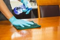 Sanitizing surfaces cleaning kitchen table with disinfectant spray bottle with towel and gloves. COVID-19 prevention.