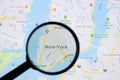 New York city on Google Maps on Apple iMac monitor screen under a magnifying glass.