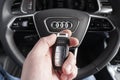 Close up of Audi A6 car keys in driver hand. Black leather interior of a modern car. Audi A6 S-Line interior details. Man holding