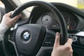 Woman`s hands on a steering wheel driving BMW X5 F15. Hands holding steering wheel. Modern Car interior details.