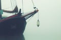Bow of a sailboat surrounded by fog.