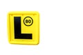 A sans-serif letter `L plate` in yellow color which must be affixed to the front and back of a vehicle in many countries.