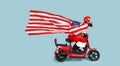 Santa with a big flying usa flag in the form of a raincoat and a helmet rides a red electric scooter Royalty Free Stock Photo