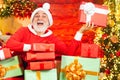 Santa with Christmas gift. Portrait of funny Santa man indoors with Christmas gift. Bearded man having fun near