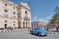 Blue retro moving along street of city Santa Clara, Cuba . Building of Caridad Theater, Vidal Park