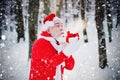 Santa Claus blowing magic snow of his hands. Portrait of happy Santa Claus walking in snowy forest and Blowing Magic Royalty Free Stock Photo