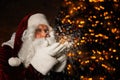 Santa Claus blowing snow against lights. Christmas time Royalty Free Stock Photo