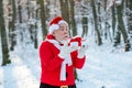 Santa Claus blows snow. Happy Santa blowing on snow. Portrait of happy Santa Claus walking in snowy forest and Blowing Royalty Free Stock Photo