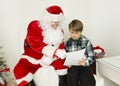 Santa Claus and a boy are reading from a paper Royalty Free Stock Photo