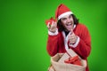 Enthusiastic man dressed up like Santa shows a little red gift taken from a big sack full of presents and expresses his apprecciat Royalty Free Stock Photo