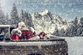 Santa Claus in a car driving to deliver some christmas presents on a sunny winter day. Blurred mountain forest background. Royalty Free Stock Photo