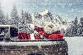 Santa Claus in a car driving to deliver some christmas presents on a sunny winter day. Blurred mountain forest background. Royalty Free Stock Photo