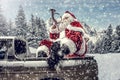 Santa Claus in a car driving to deliver some christmas presents on a sunny winter day. Blurred mountain forest background. Royalty Free Stock Photo