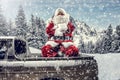 Santa Claus in a car driving to deliver some christmas presents on a sunny winter day. Blurred mountain forest background. Royalty Free Stock Photo