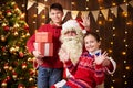 Santa Claus and child boy and girl posing together indoor near decorated xmas tree with lights, they talking, smiling and Royalty Free Stock Photo