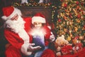 Santa Claus and child girl with bright magical gift in Christmas