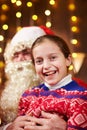 Santa Claus and child girl posing together indoor near decorated xmas tree with lights, they talking and smiling - Merry Christmas Royalty Free Stock Photo