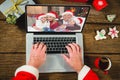 Santa claus with christmas presents having video call with happy caucasian family Royalty Free Stock Photo