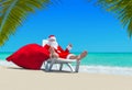 Santa Claus with Christmas sack on deckchair at palm beach Royalty Free Stock Photo