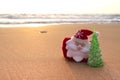 Santa Claus and Christmas tree on the beach or sandy sea shore. Christmas and New Year celebration travel concept. Royalty Free Stock Photo