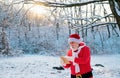 Santa Claus with Christmas wish list comes in the snow forest. Royalty Free Stock Photo