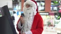 Santa Claus with a credit card near an bancomat in a large shopping center