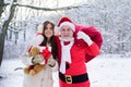 Santa Claus and daughter girl with a bag of Christmas gifts in the snow forest on winter snowy landscape. Royalty Free Stock Photo