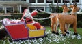 Santa Claus delivers gifts in a sleigh drawn by reindeer, decorative garden sculpture, a