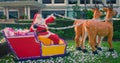 Santa Claus delivers gifts in a sleigh drawn by reindeer, decorative garden sculpture, summer Christmas