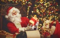 Santa Claus at desk with letters, gifts near Christmas tree Royalty Free Stock Photo