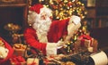 Santa Claus at desk with letters, gifts near Christmas tree Royalty Free Stock Photo
