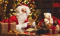 Santa Claus at desk with letters, gifts near Christmas tree Royalty Free Stock Photo