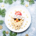 Santa Claus face made of fruits and marshmallow on a plate. Christmas food for children. Top view Royalty Free Stock Photo