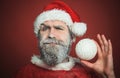 Santa Claus with frozen beard with white Christmas ball. Bearded man in Santa Claus clothes with decorative New Year toy