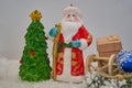 Santa Claus with a gift and a sleigh,Christmas statuette of Santa next to the Christmas tree in the snow