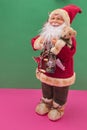 Santa Claus with gifts and an old lantern on a green and pink background. Minimalistic scene