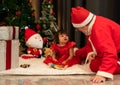 Santa Claus with girl toddler sitting together on floor at home. Christmas celebration concept Royalty Free Stock Photo