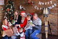 Santa Claus gives New Year gifts to big family in decorated room Royalty Free Stock Photo